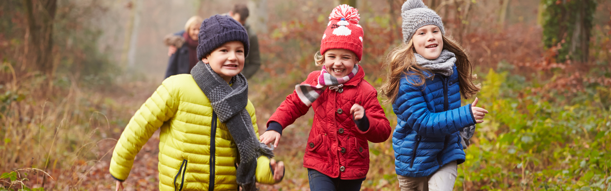 Tre glada barn springer i höstskogen