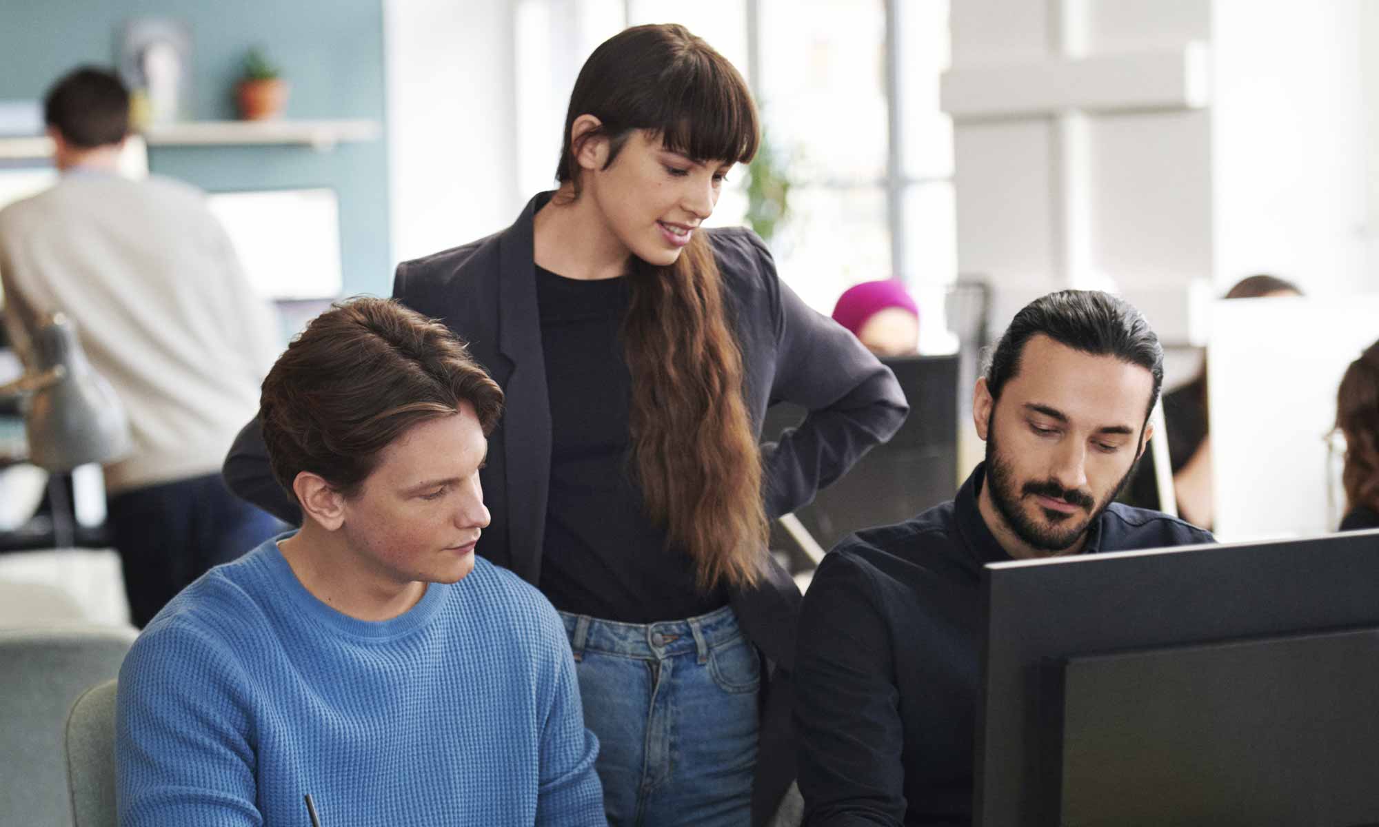 Tre kollegor på en arbetsplats framför en dator