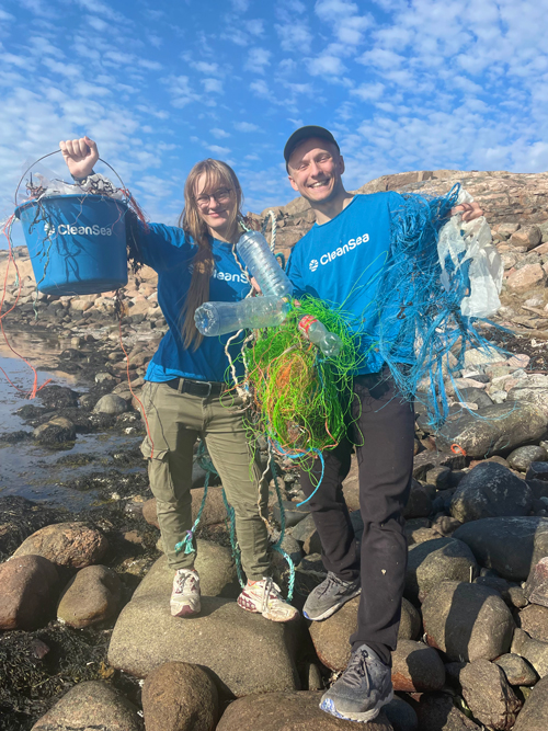 Two persons showing plastic and ghost net from beack cleanup
